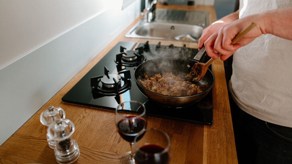 Cooking a meal on a narrowboat kitchen hob, with fresh ingredients and a glass of wine