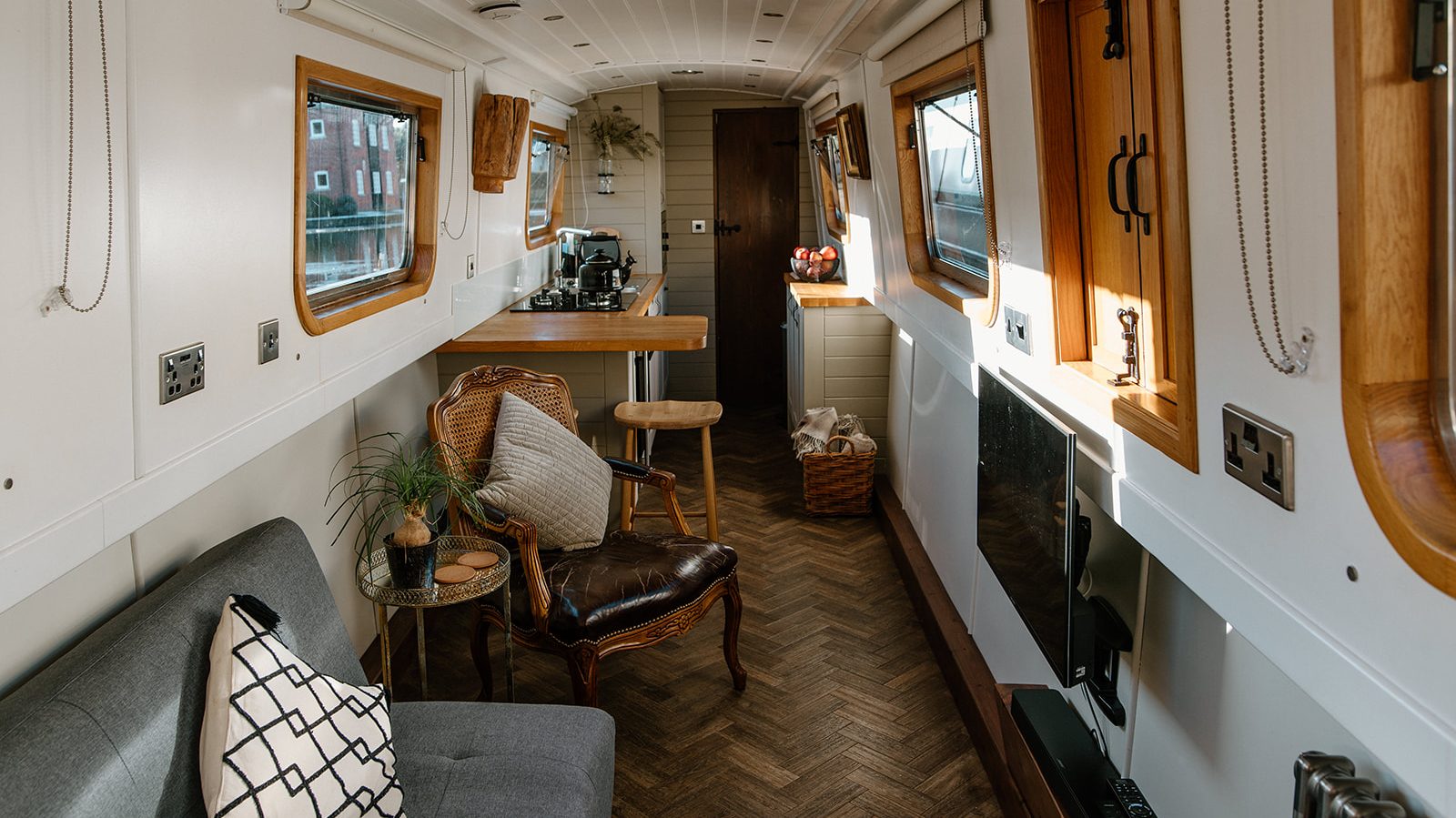 Interior of a dog friendly narrowboat with cosy seating, warm lighting and a tidy galley.